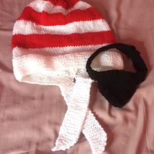 May include: A red and white striped knitted pirate hat with a white tie and a black eye patch.