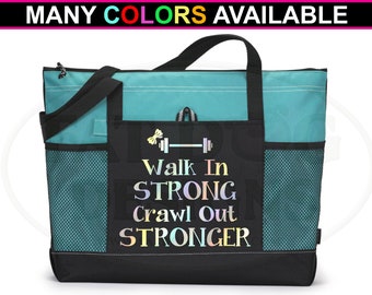 May include: A teal and black tote bag with a mesh pocket. The bag has a zipper closure and two handles. The front of the bag has a black pocket with the text "Walk In STRONG Crawl Out STRONGER" in a rainbow iridescent font.