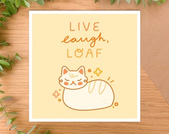 May include: A yellow card with the text "LIVE laugh, LOAF" and a cartoon white cat with orange eyes sleeping on its side.