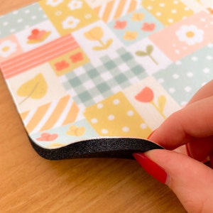 May include: A rectangular mouse pad featuring a patchwork design of pastel yellow, mint green, and soft pink squares. The pattern includes white daisies, tulips, gingham checks, polka dots, and diagonal stripes, with a thick black foam base.