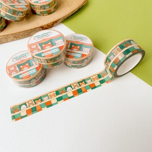 Könnte beinhalten: Washi-Tape-Rollen mit dem Thema "Cute Critters Bedtime". Das Klebeband zeigt ein sich wiederholendes Muster von Tieren in Betten und ein kariertes Design in Grün, Orange und Braun. Die Rollen tragen den Text "cute critters bedtime wash tape" und "Laurel mae art."