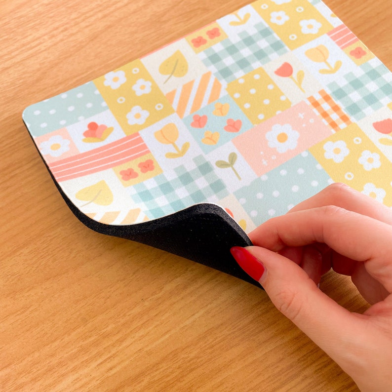 May include: A rectangular mouse pad featuring a patchwork design of pastel yellow, light blue, and soft orange squares. The pattern includes white flowers, tulips, polka dots, and gingham checks. The mouse pad has a thick black foam base layer.