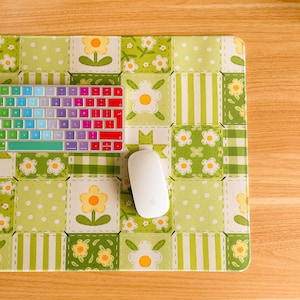 May include: A colourful keyboard, white mouse, and a floral-patterned mousepad with green and white squares. The mousepad features a patchwork design with flowers and polka dots, creating a cheerful workspace.