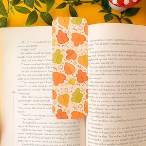Peut inclure: Un marque-page sur le thème de l'automne avec un motif de feuilles orange, jaunes et vertes sur un fond crème. Le marque-page est fait de carton épais et est parfait pour marquer votre place dans un livre.