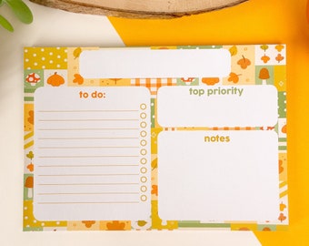 May include: A white notepad with a colorful autumn-themed design. The notepad is divided into three sections: "to do", "top priority", and "notes".