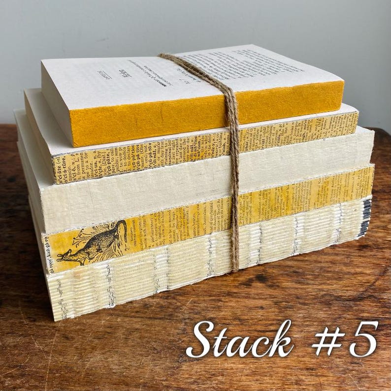 May include: A stack of five books with yellow and white covers. The books are tied together with twine. The top book has the word "elate" printed on the cover. The bottom book has a picture of a kangaroo on the cover.