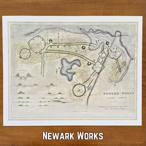 May include: A vintage map print of Newark Works, Licking County, Ohio. The map features detailed illustrations of earthworks, waterways, and topographical sections, with text indicating scale and authorship. The print is framed in white.