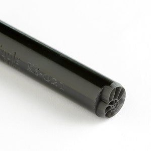 May include: A black rubber stamp with a floral design and the text "KORK-Tülle K1021" on the side.