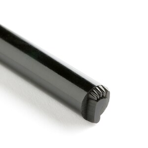 May include: A black metal stamp with a decorative design on the end.