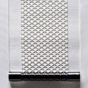 May include: A white patterned roller blind with a black metal roller at the bottom.