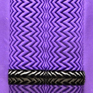 May include: Purple textured rubber surface with a black and white chevron pattern along the bottom edge.