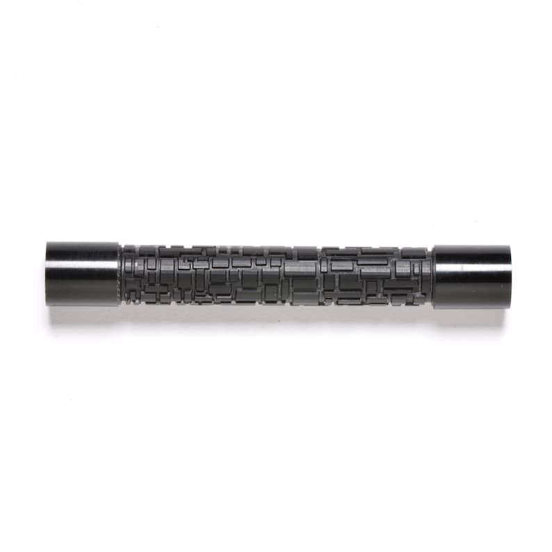 May include: A black metal rod with a textured surface. The rod has a geometric pattern.