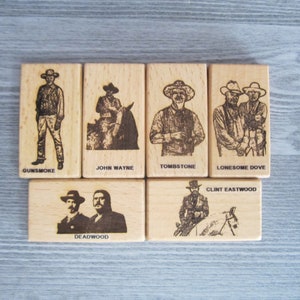 May include: Six wooden tiles with engraved images of famous Western movie stars and locations. The tiles feature images of Gunsmoke, John Wayne, Tombstone, Lonesome Dove, Clint Eastwood, and Deadwood.