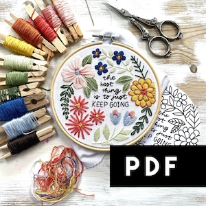 Op de afbeelding: Borduurring met een witte stoffen achtergrond met kleurrijke bloemenborduurwerk en de tekst "the best thing is to just KEEP GOING". De ring is omgeven door borduurgaren, houten wasknijpers en een schaar op een wit houten oppervlak. De tekst "PDF" staat in zwarte letters op een zwarte achtergrond.