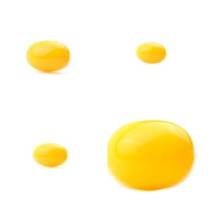 May include: Four yellow egg yolks isolated on a white background. The yolks are different sizes and shapes.