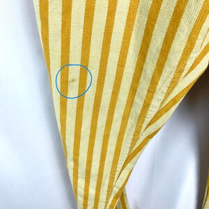K&ouml;nnte beinhalten: Nahaufnahme eines Stoffes mit gelben und cremewei&szlig;en vertikalen Streifen. Der Stoff ist leicht zerknittert und hat einen kleinen Fleck. Die Streifen sind gleichm&auml;&szlig;ig angeordnet und erzeugen ein strukturiertes Aussehen.