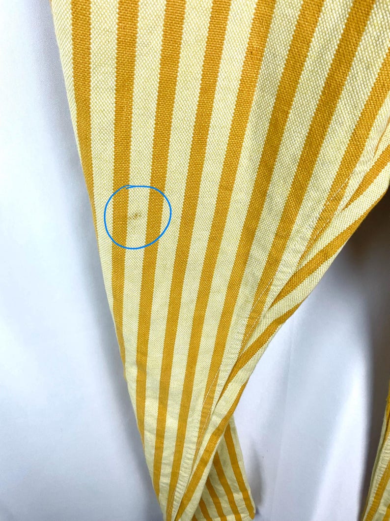 K&ouml;nnte beinhalten: Nahaufnahme eines Stoffes mit gelben und cremewei&szlig;en vertikalen Streifen. Der Stoff ist leicht zerknittert und hat einen kleinen Fleck. Die Streifen sind gleichm&auml;&szlig;ig angeordnet und erzeugen ein strukturiertes Aussehen.