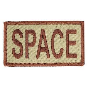 May include: A tan embroidered patch with a brown border. The patch says "SPACE" in brown letters.