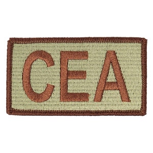 May include: Embroidered patch with the letters "CEA" in a brown color. The letters are stitched onto a light green background, framed by a brown border. The patch has a rectangular shape.