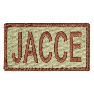 May include: A tan fabric patch with a brown embroidered name "JACCE" on it.