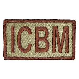 May include: Tan colored patch with brown embroidered letters that spell out "ICBM".