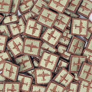 Puede incluir: Una imagen de primer plano de una pila de pequeños parches cuadrados de color verde y marrón. Cada parche presenta una imagen bordada de un avión.