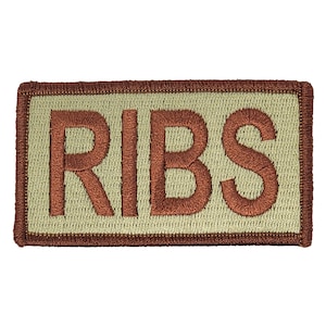 May include: A tan embroidered patch with a brown border. The patch says "RIBS" in brown lettering.