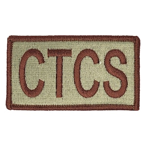 May include: Embroidered patch with the letters "CTCS" in a dark brown color. The letters are stitched onto a light green background, framed by a brown border. The patch is rectangular.