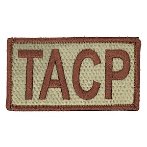 May include: A tan and brown embroidered patch with the word "TACP" in brown lettering.