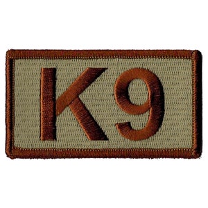 May include: A brown embroidered patch with the text "K9" on a beige background. The patch has a brown border.