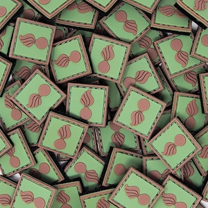 May include: A collection of square patches with a green background and a brown emblem. The emblem features a stylized design with a circular base and a flame-like element above it. The patches have a brown border.