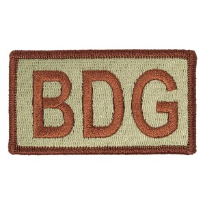 May include: A beige rectangular patch with a brown embroidered border and the word "BDG" in brown lettering.