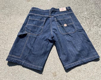 May include: Dark blue denim shorts with multiple pockets and a utility pocket. The shorts have a classic five-pocket design with reinforced stitching and a small logo patch on the back pocket. The shorts are made of a durable denim material.
