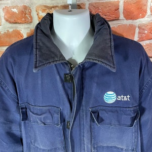 May include: A navy blue work jacket with a black corduroy collar and a large embroidered AT&T logo on the chest.