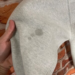 Puede incluir: Primer plano de una sudadera gris con algunas manchas de color marr&oacute;n claro. La tela es suave y texturizada.