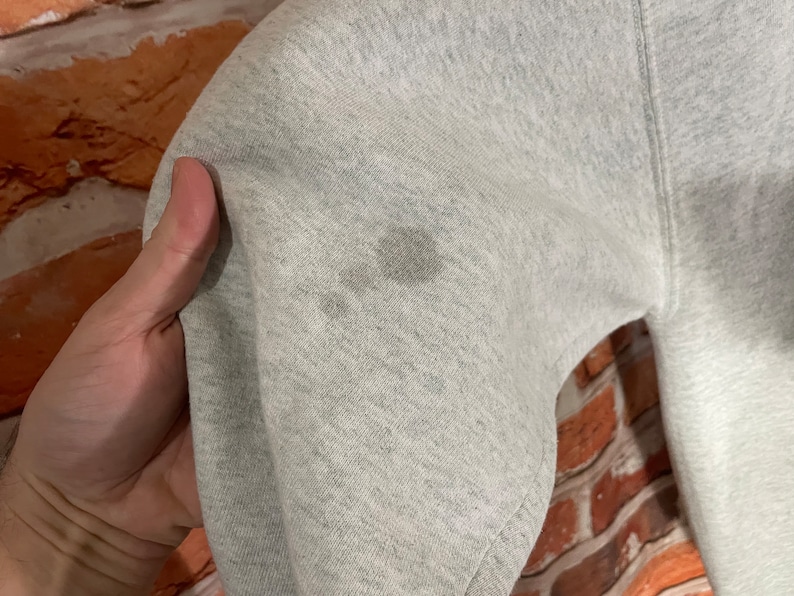 Puede incluir: Primer plano de una sudadera gris con algunas manchas de color marr&oacute;n claro. La tela es suave y texturizada.