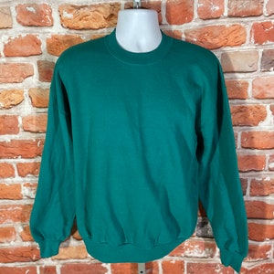 May include: A plain, dark green sweatshirt with long sleeves and a crew neck.