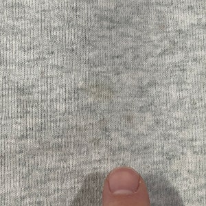 Puede incluir: Primer plano de una tela gris texturizada con una sutil mancha marr&oacute;n claro.