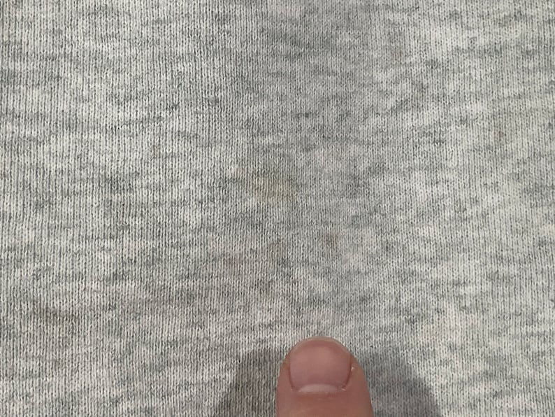Puede incluir: Primer plano de una tela gris texturizada con una sutil mancha marr&oacute;n claro.