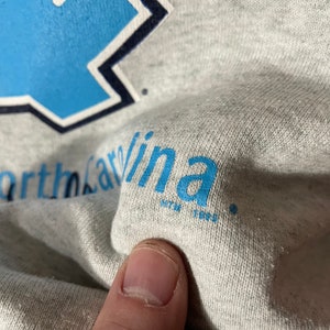 Puede incluir: Sudadera gris con texto azul que dice "University of North Carolina".
