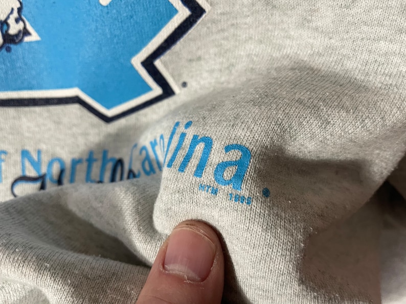 Puede incluir: Sudadera gris con texto azul que dice "University of North Carolina".