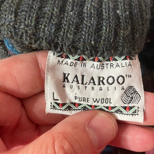 May include: A close-up of a gray wool sweater tag with the text "Made in Australia", "KALAROO&trade; AUSTRALIA", "PURE WOOL" and a size "L" label.