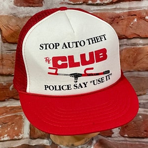 May include: Red and white trucker hat with the text "STOP AUTO THEFT THE CLUB POLICE SAY "USE IT"" and a black and white illustration of a car club.