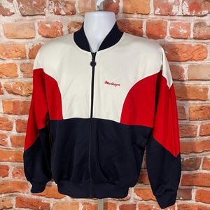 May include: A white, red, and navy blue color block zip-up jacket with the text "Mr. Draper" embroidered on the front.