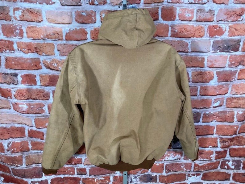May include: A brown hooded jacket with a zipper closure. The jacket has a brown ribbed knit waistband and cuffs.
