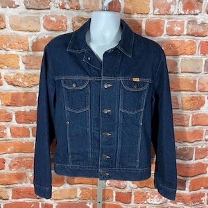 May include: A dark blue denim jacket with a button closure and two front pockets. The jacket has a classic style and is made of a durable material.