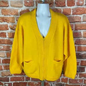 May include: A bright yellow knitted cardigan with a zipper closure and two pockets. The cardigan has a V-neck and long sleeves.