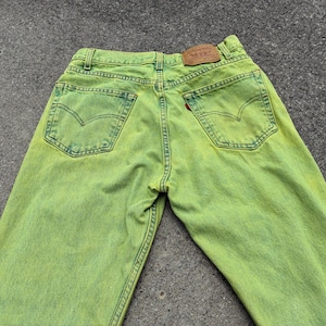 Op de afbeelding: Een limoengroene spijkerbroek van denim met een hoge taille en riemlussen, twee achterzakken met gebogen stiksels, een bruin leren merklabel op de tailleband en een klein rood labeltje op de rechterachterzak.