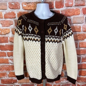 May include: A white and brown cardigan with a geometric pattern. The cardigan has a button-up front and long sleeves.