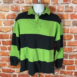 May include: A long-sleeved rugby shirt with black and green horizontal stripes. The shirt has a button-up collar and a button placket.